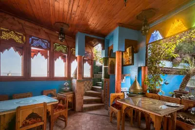 a dining room with tables and chairs and windows at Riad Hiba in Meknès