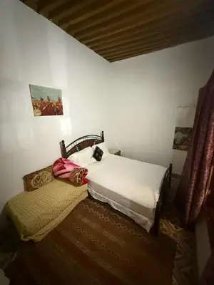 a bedroom with a white bed and a couch at Dar Elkorchi in Fès