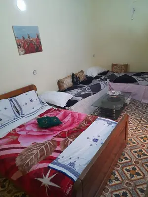 a room with two beds and a table at Dar Elkorchi in Fès