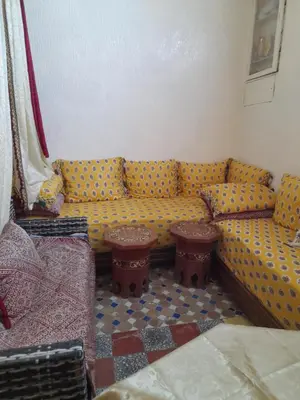 a living room with a yellow couch and two tables at Dar Elkorchi in Fès