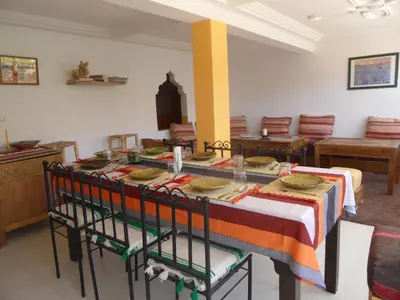 a dining room with a table and chairs and a room with at Gite Tigmi Azrur in Tabant