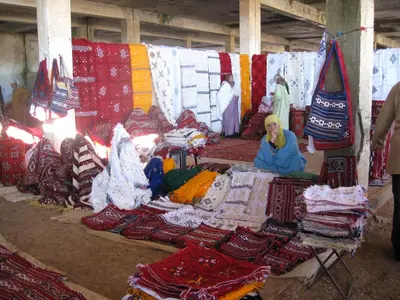 a group of people sitting in a market with carpets at Riad Menthe Et Citron in Meknès
