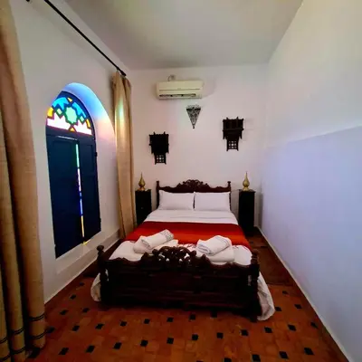 a bedroom with a bed with a red bedspread and a window at Riad Menthe Et Citron in Meknès