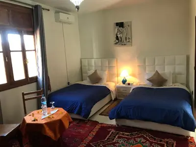 a bedroom with two beds and a table and a window at Riad Villa Midelt in Midelt