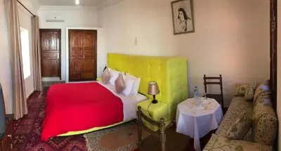 a bedroom with a red and yellow bed and a table at Riad Villa Midelt in Midelt