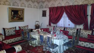 a living room with a table and red chairs at Riad Villa Midelt in Midelt