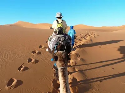 two people riding a camel in the desert at Hotel Marmar in Ouarzazate