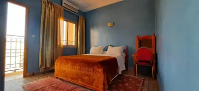 a bedroom with a bed and a red chair at Hotel Marmar in Ouarzazate