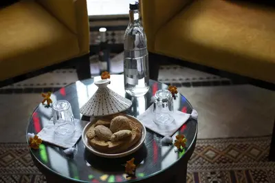 a glass table with a bowl of cookies and a bottle at Palais Amani in Fès