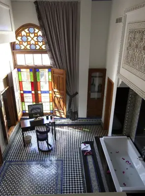 a living room with a tub and a stained glass window at Palais Amani in Fès