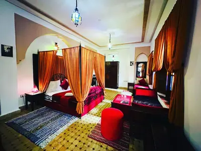 a bedroom with two beds and a red chair at Riad Ahlam in Fès