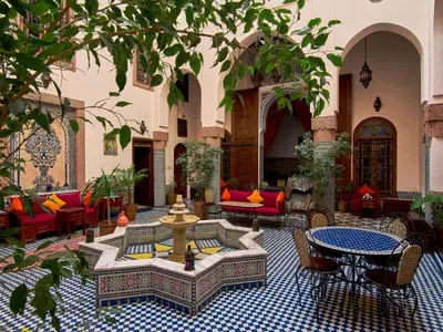 a courtyard with a fountain and tables and chairs at Riad Ahlam in Fès