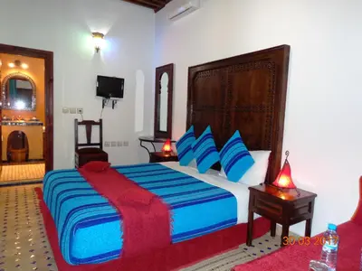 a bedroom with a large bed with blue and red sheets at Riad Ahlam in Fès