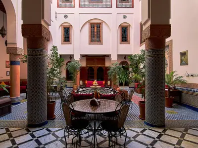 a lobby with a table and chairs in a building at Riad Ahlam in Fès