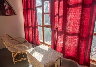 a room with a table and a window with red curtains at Bassatine Skoura in Skoura
