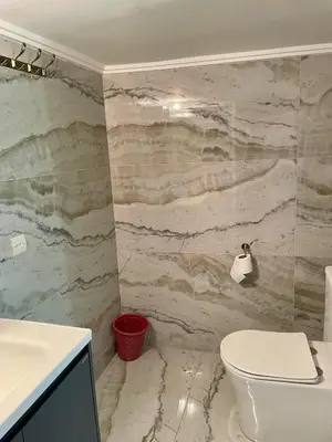 a bathroom with a white toilet and a marble wall at Bassatine Skoura in Skoura