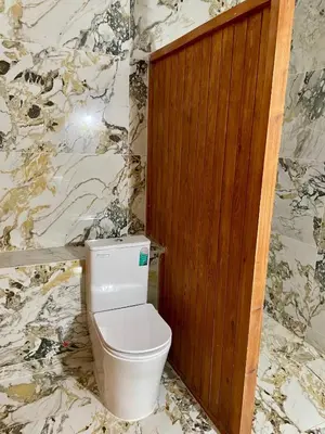 a bathroom with a toilet and a marble wall at Bassatine Skoura in Skoura