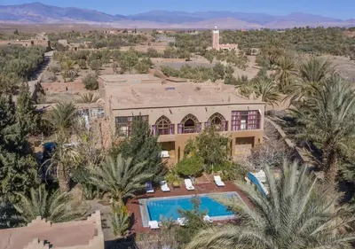 an aerial view of a house with a swimming pool and palm trees at Bassatine Skoura in Skoura
