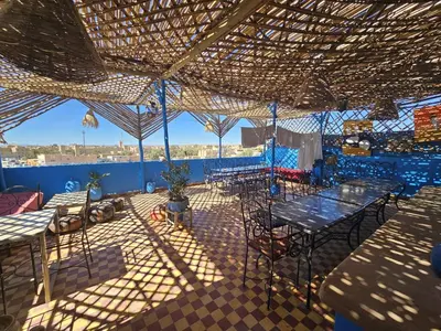 a patio with tables and chairs under a roof at Panorama chez Hamid in Rissani
