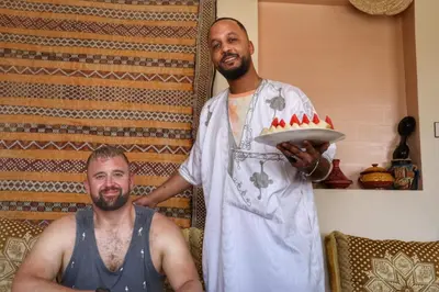 two men in a kitchen with a cake on a plate at Panorama chez Hamid in Rissani