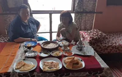 a man and a woman sitting around a table with food at Panorama chez Hamid in Rissani