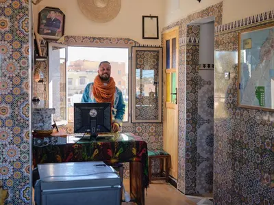 a man standing at a desk with a computer at Panorama chez Hamid in Rissani