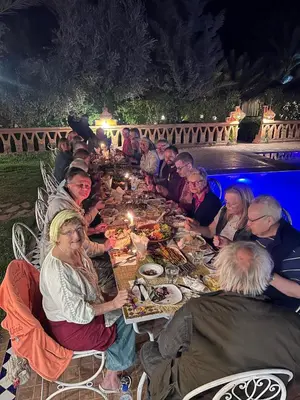 a group of people sitting at a long table eating food at Paradis Touareg in Zagora