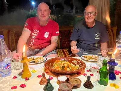 two men sitting at a table with plates of food at Paradis Touareg in Zagora