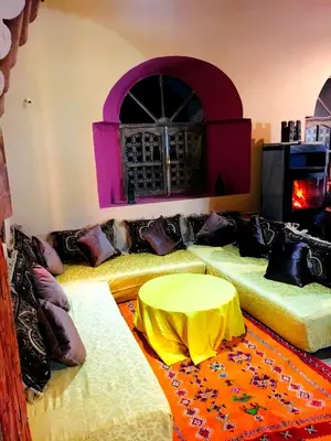 a room with three beds with a table in it at Kasbah Tiriguioute in Skoura