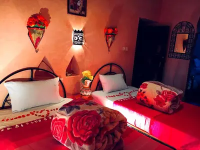 two beds in a room with flowers on the wall at Kasbah Tiriguioute in Skoura