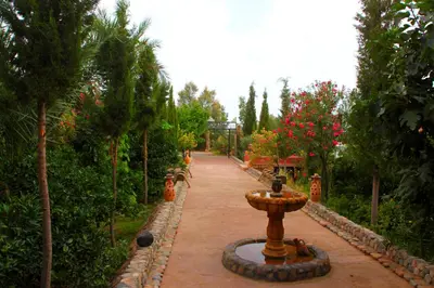 a garden with a fountain in the middle of a path at Kasbah Tiriguioute in Skoura
