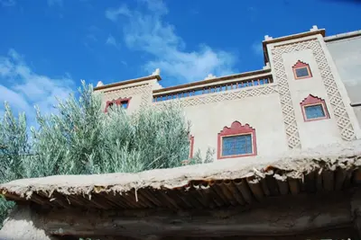 a building with a tile roof with trees in the background at Dar Calme Chez El Bouhali in Skoura