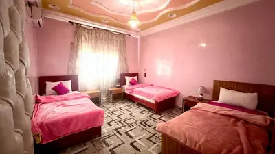 two beds in a room with pink walls at Dar Calme Chez El Bouhali in Skoura