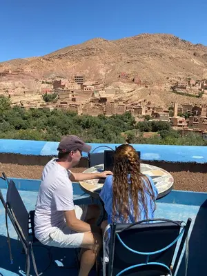 a man and a woman sitting at a table with a laptop at Labyrinth Kasbah Dades in Ait Ben Ali