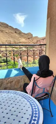 a person sitting in a chair on a patio with a table at Labyrinth Kasbah Dades in Ait Ben Ali