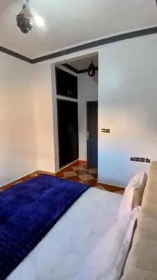 a bedroom with a large bed and a blue rug at Residence Rosas in Ouarzazate