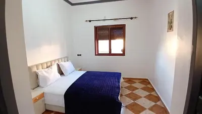 a bedroom with a bed with a blue blanket at Residence Rosas in Ouarzazate