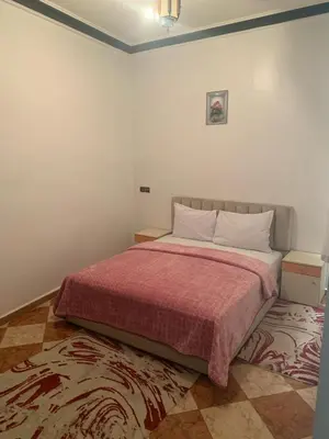a bedroom with a large bed with a red blanket at Residence Rosas in Ouarzazate