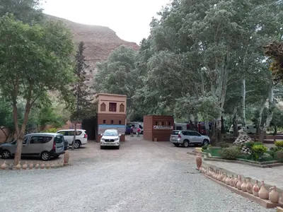 a parking lot with cars parked in front of a building at Hotel Restaurant Camping Berbère de la Montagne in Imdiazene