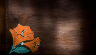 a painting of an orange flower on a wooden table at Riad Al Bartal in Fès