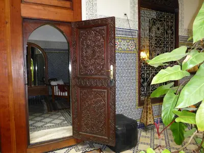a large wooden door in a room with a mirror at Riad Al Bartal in Fès