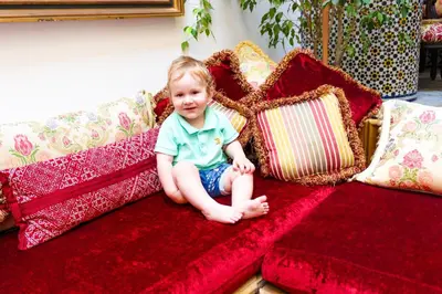 a little girl sitting on a couch with pillows at Riad-Boutique Borj Dhab Fez in Fès
