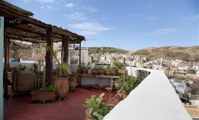 a balcony with potted plants and a view of a city at Dar KamalChaoui in Bhalil