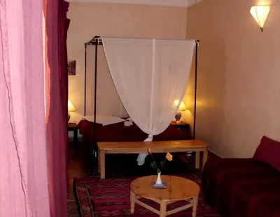 a room with a bed and a table with a curtain at Dar Qamar in Agdz