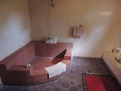 a bathroom with a brick tub and a sink at Dar Qamar in Agdz