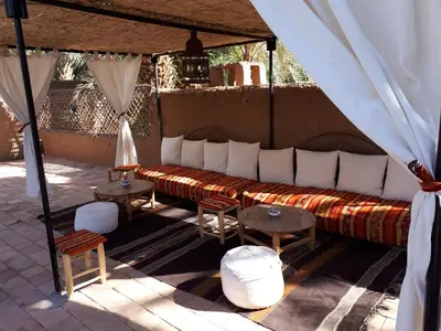 a couch in a tent with tables and chairs at Dar Qamar in Agdz