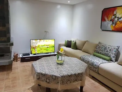 a living room with a couch and a tv at Chalet Asmoun in Imouzzer Kandar