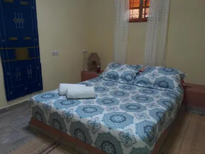 a bedroom with a bed with a blue and white comforter at Camping Auberge Zebra in Ouzoud