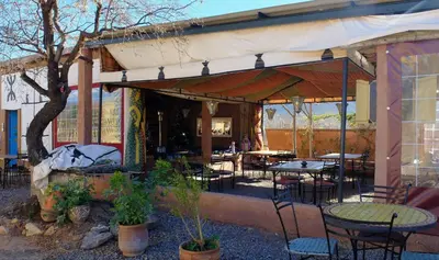 an outdoor patio with tables and chairs and a building at Camping Auberge Zebra in Ouzoud