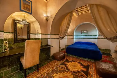a bedroom with a blue bed and a mirror at Hôtel Riad Dar Daïf in Ouarzazate